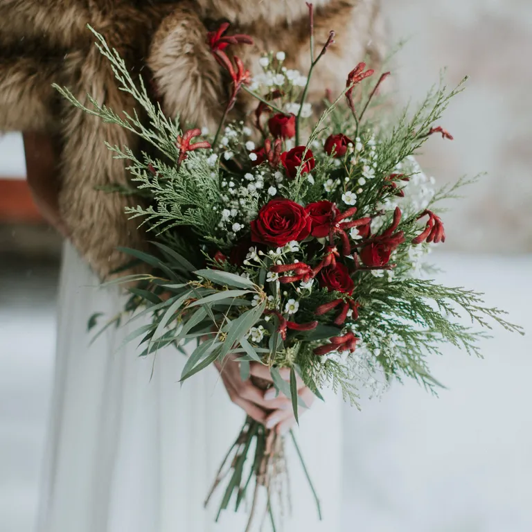 Infuse natural beauty into your celebration with bouquets featuring lush evergreen branches, pinecones, and perhaps a hint of red berries