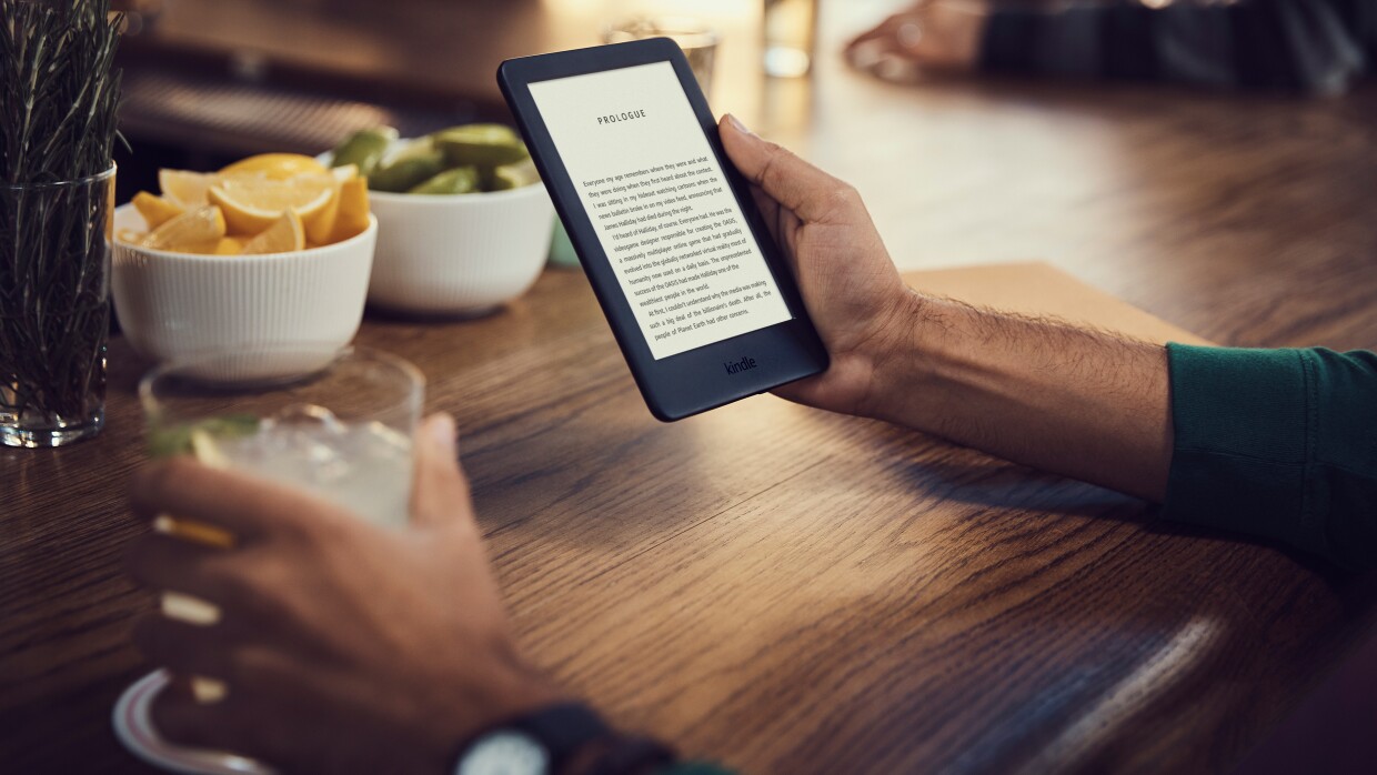 man reading a book on e-reader and drinking at a bar